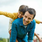 Homme jouant avec son fils qui tient sur son dos